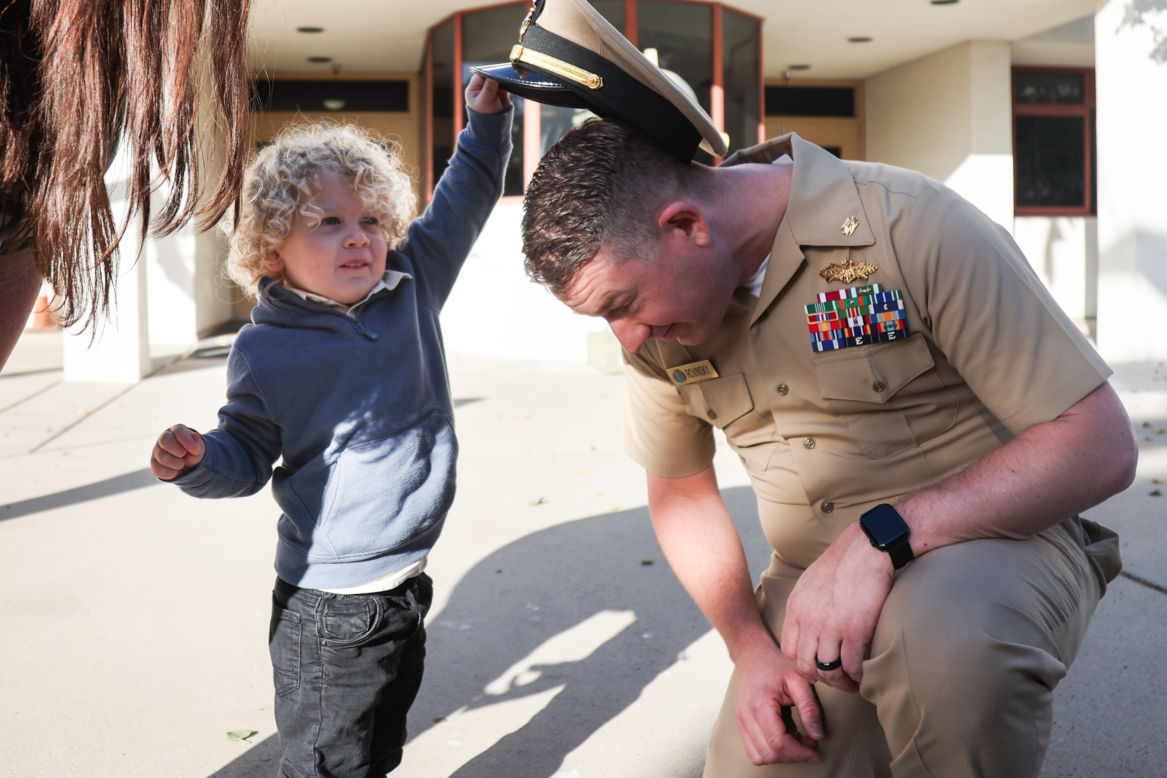 In a photo taken by 	Petty Officer 1st Class Justin Rayburn a young boy takes a hat off a U.S. service member.