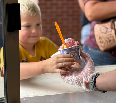 A boy received his ice cream through the window at Scoops.