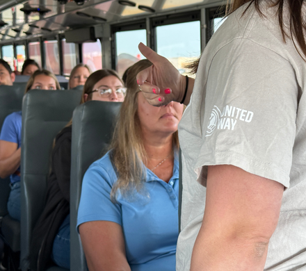Heartland United Way staff member talks to Tour of Agencies 2025 participants on the bus.