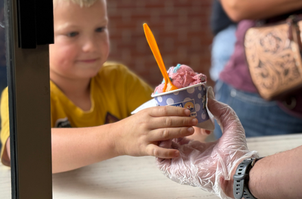 A boy received his ice cream through the window at Scoops.