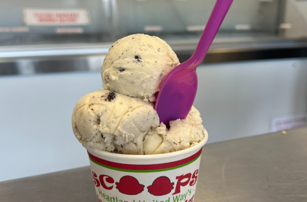 A spoon sits in a bowl of ice cream inside the Scoops Ice Cream Parlor.