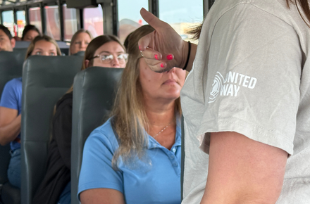 Heartland United Way staff member talks to Tour of Agencies 2025 participants on the bus.