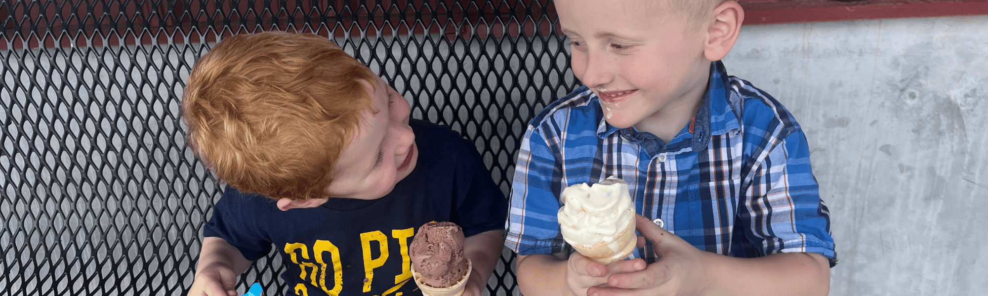 Two boys eat ice cream outside Scoops Ice Cream Parlor.