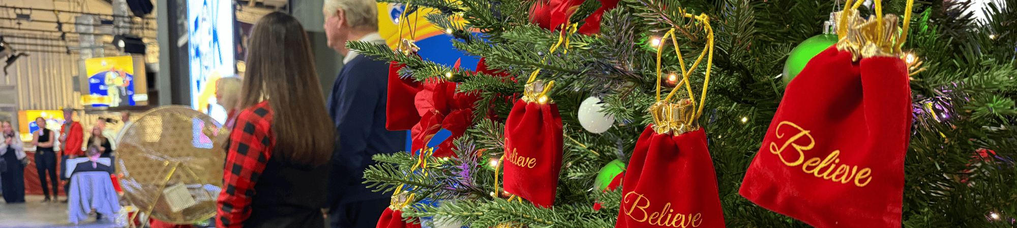 Red bags with "Believe" on them hang on a tree behind Kent and Tonja Brown.