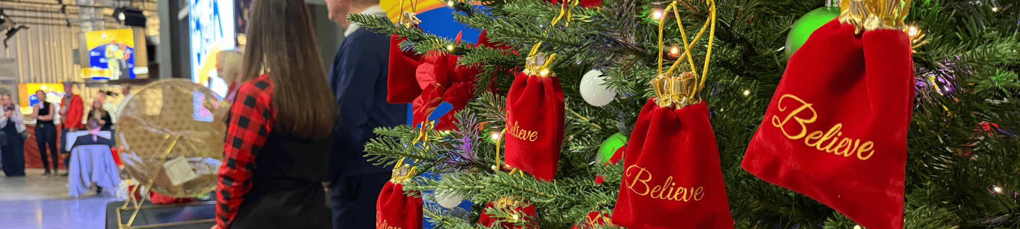 Red bags with "Believe" on them hang on a tree behind Kent and Tonja Brown.