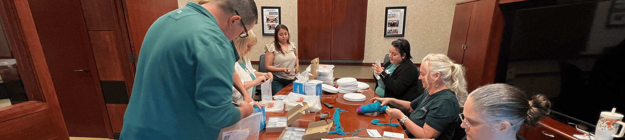 First National Bank employees gather around a conference room table to assemble packets for local nonprofits during their own 2025 Day of Action.