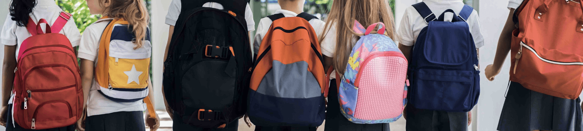 Kids wearing backpacks stand in line.
