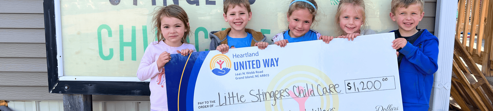 Kids at Little Stingers Child Care smile with a Rural Community Impact Grant check in 2025.
