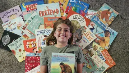 Vandaley Foulk lies on top of her entire Dolly Parton's Imagination Library collection in 2025.