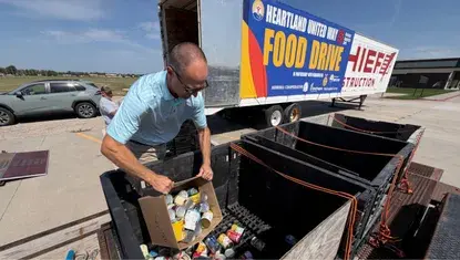 Volunteer helps dump canned food into a box at Heartland United Way Annual Food Drive in 2026.